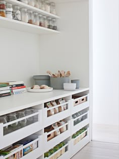 an organized pantry with white shelves and drawers