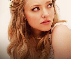 a close up of a person with long hair and flowers in her hair, looking at the camera