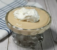 a dessert with whipped cream on top in a glass dish next to a blue and white towel