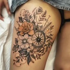 a woman's thigh with flowers and a compass tattoo