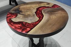 a wooden table with red and black designs on it's top, sitting in a room