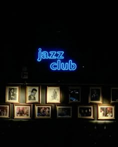 a group of framed photographs sitting on top of a wall next to a neon sign