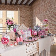 a table with candy and candies on it in front of a brick wall at a wedding