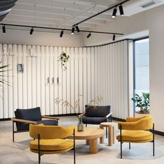 an office lobby with yellow chairs and black couches in front of large windows that have vertical blinds on them