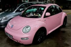 a pink car parked next to other cars in a parking lot