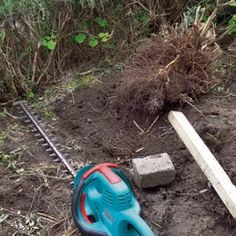 a cordless hedge trimmer laying on the ground next to a pile of dirt