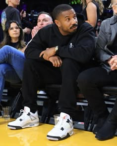 a man sitting on top of a bench next to another person wearing white shoes and black jacket