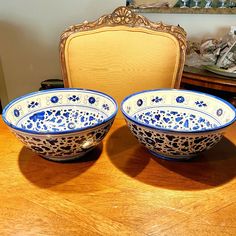 two blue and white bowls sitting on top of a wooden table next to a chair