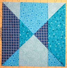 a blue and white patchwork quilt on top of a cutting board next to a ruler