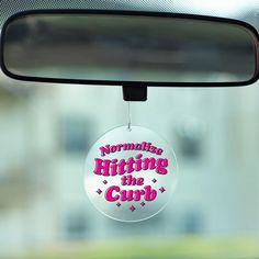 a car mirror with the words normalizing hitting the cup hanging from it's side