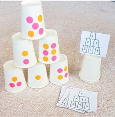 a group of paper cups sitting on top of a table next to matching cards and markers