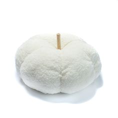 a white stuffed animal sitting on top of a white tablecloth covered floor cushion with a wooden stick sticking out of it's center