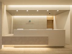 an empty reception area with white walls and lights on the ceiling is lit by recessed lighting