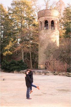 a man and woman standing next to each other in front of a castle like structure