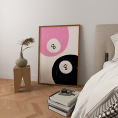 a bedroom with a bed, nightstand and art work on the wall next to it