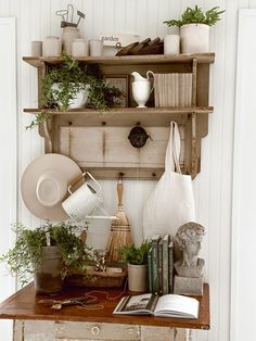 a shelf filled with books and plants on top of a wooden table next to a white door