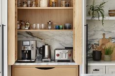 a kitchen with marble counter tops and wooden shelves filled with coffee maker, toaster, and other items