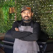 a man standing with his arms crossed in front of a green wall and grilling pans