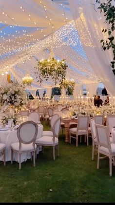 an outdoor tent with tables and chairs set up for a wedding reception in the grass