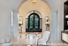 a living room filled with furniture and a large arched doorway that leads to a foyer