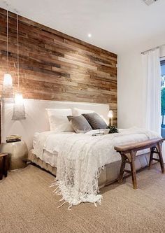 a large bed sitting next to a window in a room with wood paneling on the wall