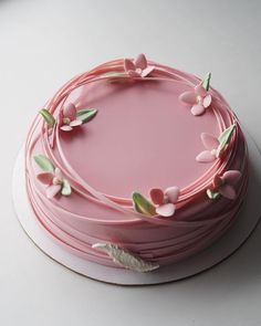 a pink cake decorated with flowers and leaves