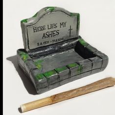 there is an ashtray with a wooden stick next to it and a grave marker