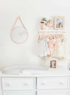 a baby's room with white furniture and pink accessories on the wall above it