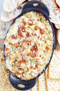 a blue skillet filled with cheese and nuts on top of crackers next to bread