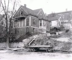 an old black and white photo of a house on a hill with a wagon parked in front of it