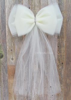 a white bow tied to the side of a wooden fence with tulle netting around it