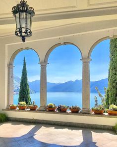 an outdoor area with potted plants and large windows overlooking the water's edge