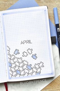 an open notebook with puzzle pieces on it and the word april written in black ink