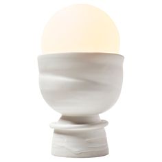 an egg sitting on top of a white object with a light bulb in it's center