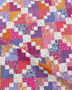 a colorful quilt with many different patterns on the top and bottom half, including pinks, purples, oranges, and white