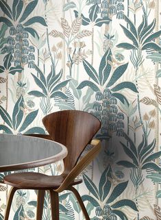 a chair sitting in front of a wallpapered with leaves and plants on it