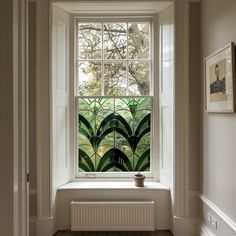 a window in a white room with green plants on the windowsill and wood flooring