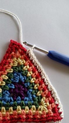 the crochet triangle is being worked on by a blue handled needle and thread