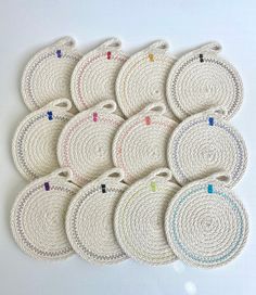 small white coasters with colorful pins on them are arranged in a row and placed next to each other