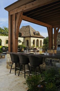 an outdoor kitchen and dining area with wine glasses on the table in front of it