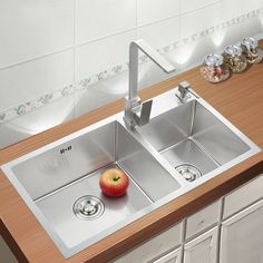 a kitchen sink with two faucets and an apple on the counter