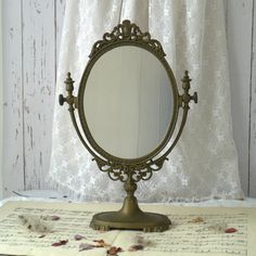 a mirror sitting on top of a table next to a sheet of music paper and a curtain