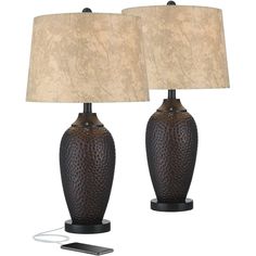 two black ceramic table lamps with beige shades on each lamp, one is turned off and the other has a cell phone in front of it