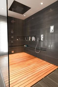 an image of a bathroom with wood flooring and gray tile on the shower wall