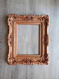 an ornate gold frame on a wooden wall with a wood floor in the back ground