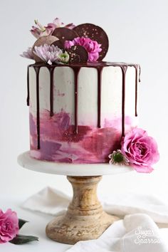 a white and pink cake with chocolate hearts on top, drizzled with fudge