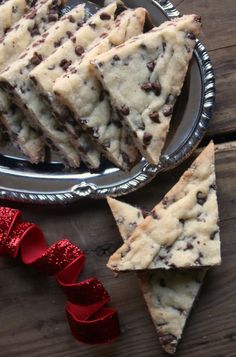 several pieces of chocolate chip cookie bars on a plate next to a red bow and ribbon