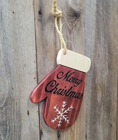 a red mitt hanging from a rope on a wooden fence that says merry christmas