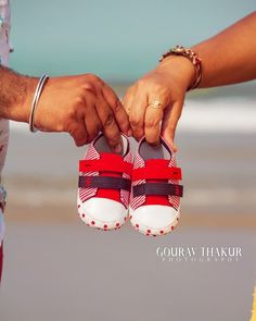 a close up of two people holding hands with shoes on the beach in front of them