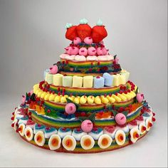 a multi - tiered cake is decorated with strawberries and other candies on it